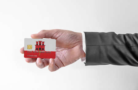 Bank credit plastic card with flag of Gibraltar holding man in elegant suitの写真素材