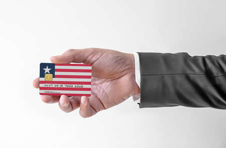 Bank credit plastic card with flag of Liberia holding man in elegant suitの写真素材