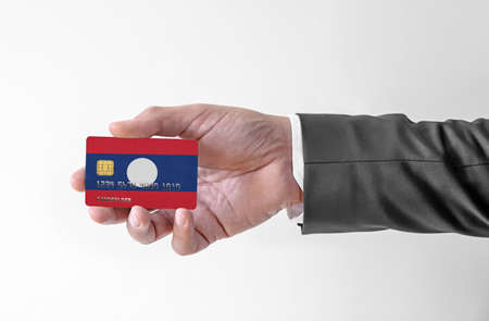Bank credit plastic card with flag of Laos holding man in elegant suitの写真素材