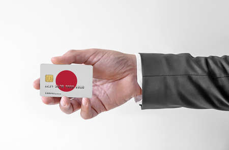 Bank credit plastic card with flag of Japan holding man in elegant suitの写真素材