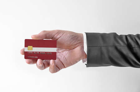 Bank credit plastic card with flag of Latvia holding man in elegant suitの写真素材