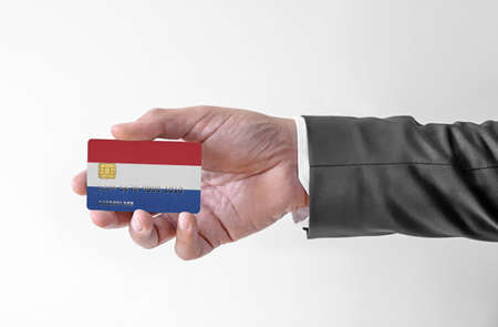 Bank credit plastic card with flag of Netherlands holding man in elegant suitの写真素材
