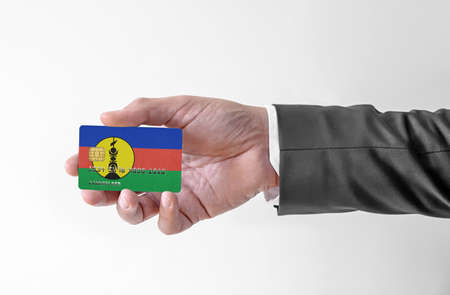 Bank credit plastic card with flag of New Caledonia holding man in elegant suitの写真素材