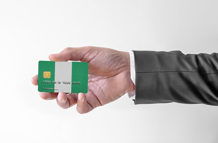 Bank credit plastic card with flag of Nigeria holding man in elegant suitの写真素材