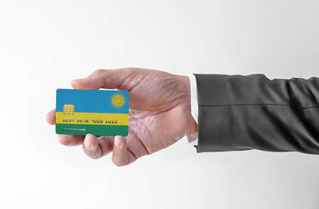 Bank credit plastic card with flag of Rwanda holding man in elegant suitの写真素材
