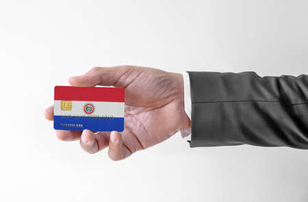 Bank credit plastic card with flag of Paraguay holding man in elegant suitの写真素材