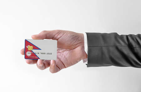 Bank credit plastic card with flag of Nepal holding man in elegant suitの写真素材