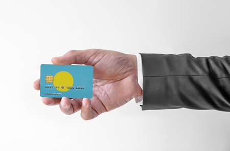 Bank credit plastic card with flag of Palau holding man in elegant suitの写真素材