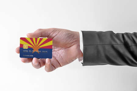 Bank credit plastic card with flag of USA state Arizona holding man in elegant suitの写真素材