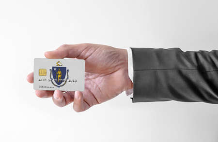 Bank credit plastic card with flag of USA state Massachusetts holding man in elegant suitの写真素材