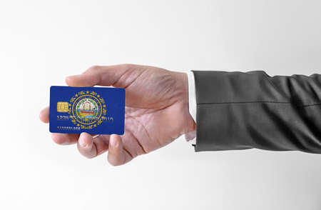 Bank credit plastic card with flag of USA state New Hampshire holding man in elegant suitの写真素材