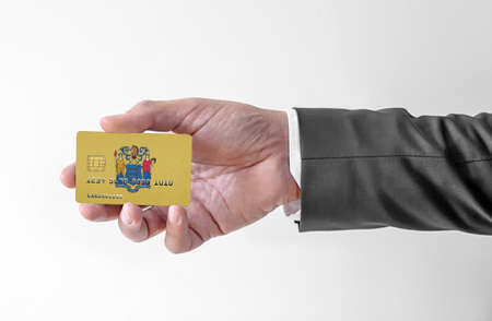 Bank credit plastic card with flag of USA state New Jersey holding man in elegant suitの写真素材