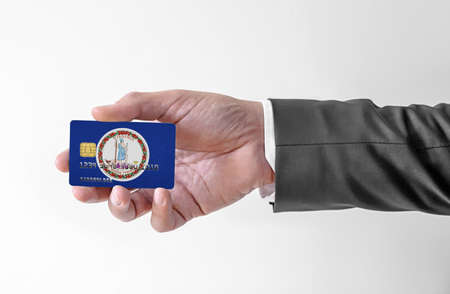 Bank credit plastic card with flag of USA state Virginia holding man in elegant suitの写真素材