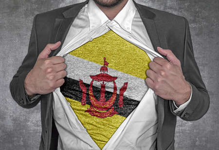 Business man show t-shirt flag of Brunei rips open his shirtの写真素材