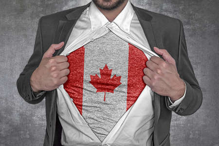 Business man rips open his shirt to show t-shirt with flag of Canadaの写真素材