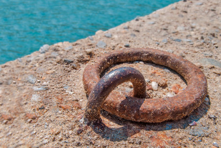 Old iron mooring cleat on a concrete pier