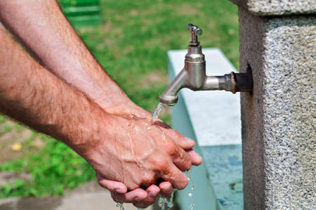 Man washing hand with water from water tap in parkの写真素材