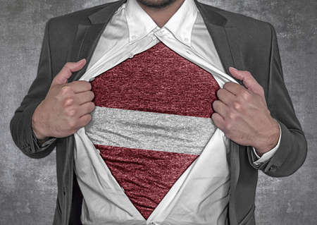 Business man show t-shirt flag of Latvia rips open his shirtの写真素材