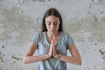 Gorgeous young caucasian female holding hands in namaste or prayerの写真素材