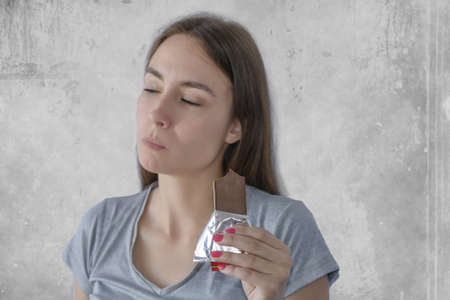 Portrait of a woman with closed eyes eating a chocolate bar and enjoyingの写真素材