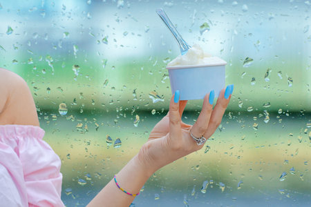 Hand of a girl holding neapolitan ice cream scoops in blue cup