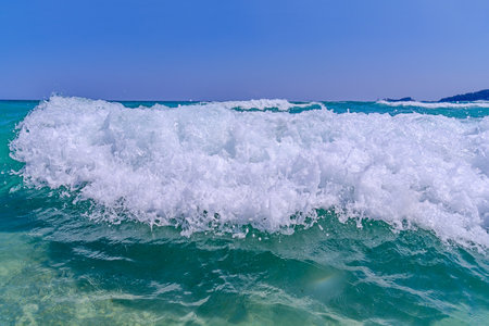 Big sea foamy wave with clean blue sky backgroundの写真素材