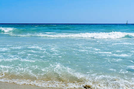 Big wave of ocean on sandy beach with blue clean skyの写真素材