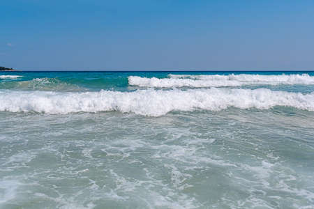Several sea foamy wave with blue clean skyの写真素材