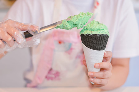 Spoon for ice cream pouring a black tasty cone in shop