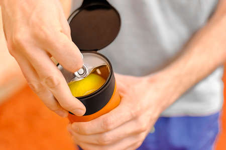 Tennis player opening new pack of balls from metal can closeの写真素材