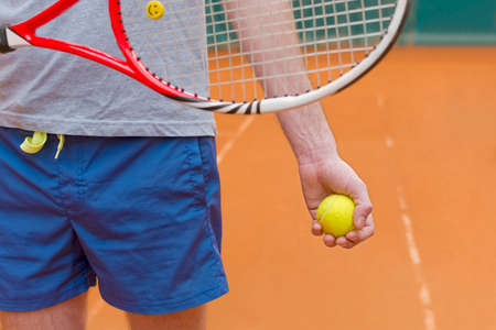 Tennis player holding racket and yellow ball on the courtの写真素材