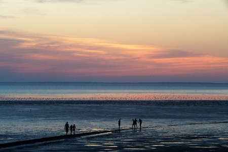 people on a breakwater during the sunsetの写真素材