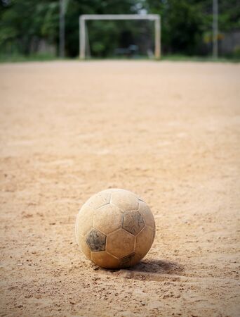 An old soccer ball on ground, goal is the background の写真素材