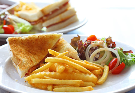 Delicious club sandwich with french fries and salad