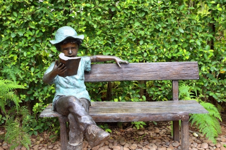 Boy reading book sculpture in the garden の写真素材