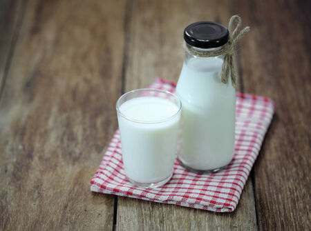 Bottle of fresh milk and glass on wooden tableの写真素材