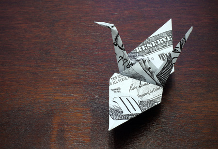 origami crane from a money note on wood tableの写真素材
