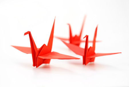 Traditional Japanese origami crane made of red paper over white backgroundの写真素材