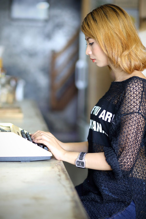 attractive asian woman using typewriter in the cafeの写真素材