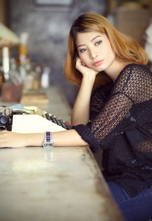 attractive asian woman using typewriter in the cafeの写真素材