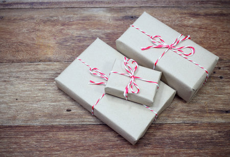 brown paper parcel tied with red and white string on wood table