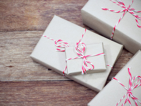 brown paper parcel tied with red and white string on wood table