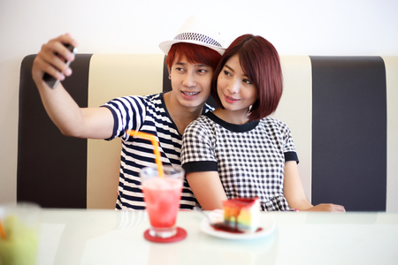 young couple taking selfie in coffee shop.の写真素材