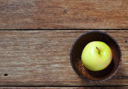 top view yellow apple in wood bowl on tableの写真素材