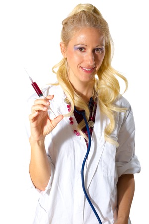 Attractive smiling blonde lady nurse standing with syringe in hand after drawing blood and stethoscope around neck, isolated on white background.の写真素材