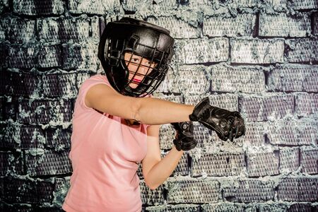 Beautiful woman during her training for combat sport. Concept of strength, concentration, determination but also femininity. The woman wears a protective helmet and glovesの写真素材
