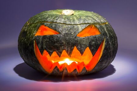 Scary Halloween Pumpkin Head glowing al night. Dark Blue and Purple Background. Jack-o-lantern.の写真素材