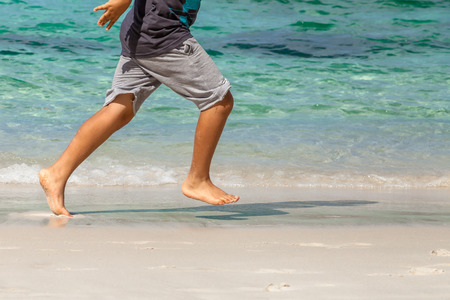 Child closeup legs only runs on the beach barefoot.の写真素材