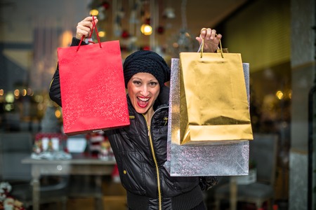 Cravings woman holding shining shopping bags during Christmas sales at shop window.の写真素材
