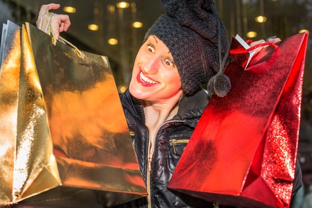 Portrait of a compulsive cravings woman holding shining shopping bags for Christmas.の写真素材